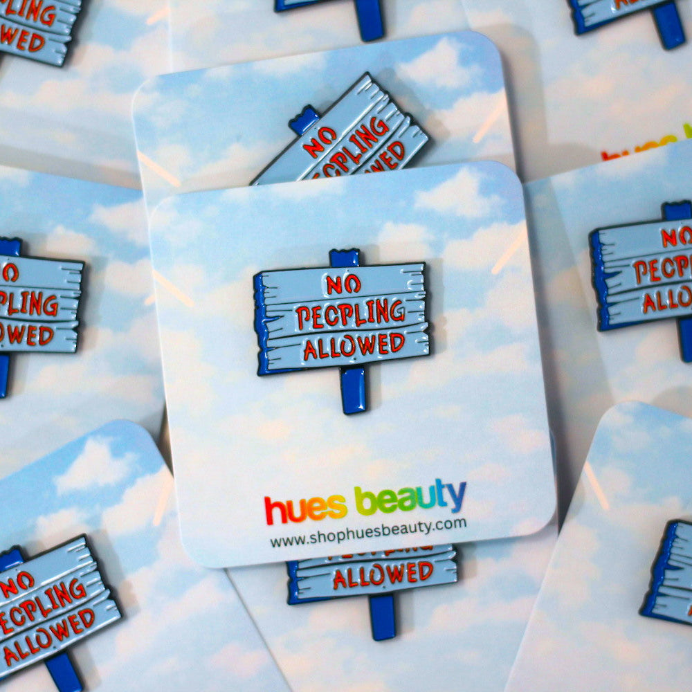 A set of square coasters with rounded corners featuring a sky-blue and white cloud pattern. Each coaster displays a wooden sign graphic that reads 'NO PEOPLING ALLOWED' in red text, with the brand name 'hues beauty' and website printed at the bottom.