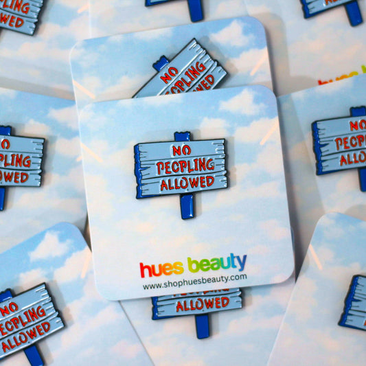A set of square coasters with rounded corners featuring a sky-blue and white cloud pattern. Each coaster displays a wooden sign graphic that reads 'NO PEOPLING ALLOWED' in red text, with the brand name 'hues beauty' and website printed at the bottom.
